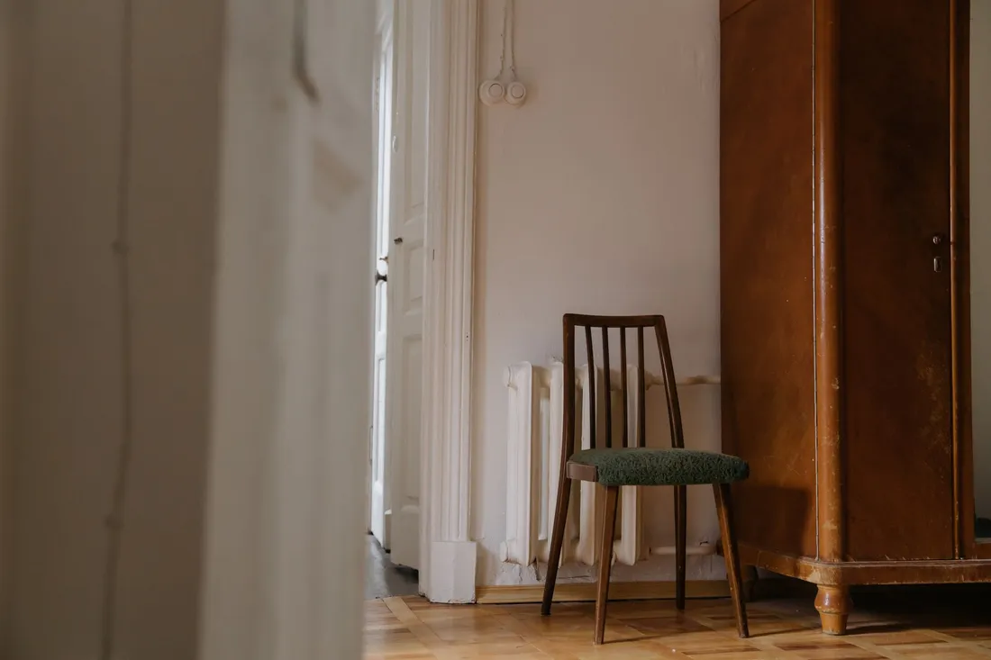 Alter Holzstuhl neben einem Kleiderschrank in einer stillen Altbauwohnung