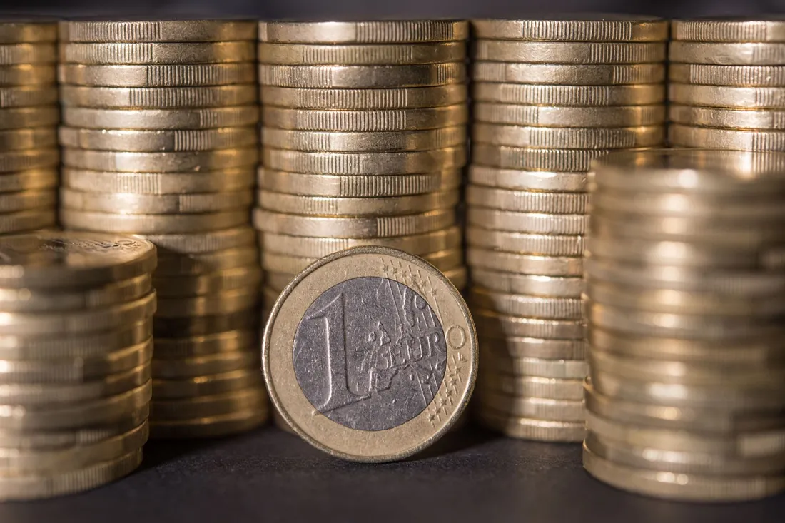 Gestapelte Euromünzen mit einer aufrecht stehenden Ein-Euro-Münze davor